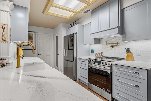 kitchen featuring stainless steel appliances, a sink, visible vents, backsplash, and gray cabinets