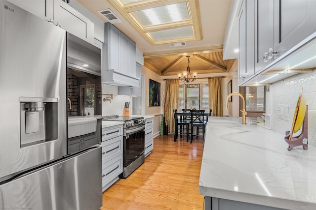 kitchen with stainless steel appliances, backsplash, visible vents, a chandelier, and light wood-style flooring