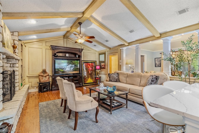 living area with a ceiling fan, vaulted ceiling with beams, light wood-type flooring, visible vents, and decorative columns