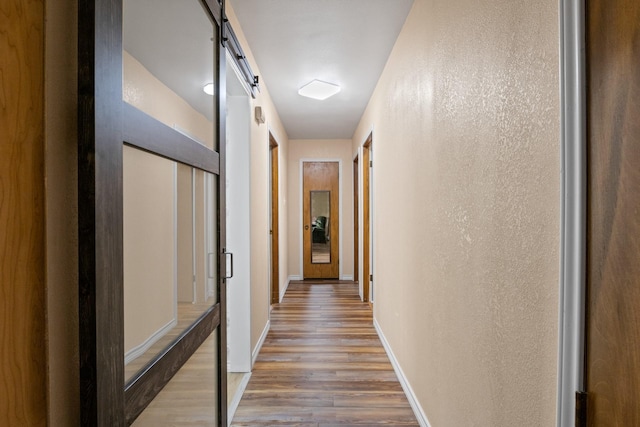 314 Cedar, Mount Pleasant, TX 75455 - hall with a barn door, wood finished floors, baseboards, and a textured wall