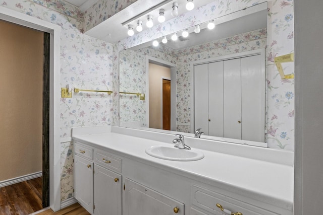 314 Cedar, Mount Pleasant, TX 75455 - bathroom with baseboards, vanity, wood finished floors, and wallpapered walls
