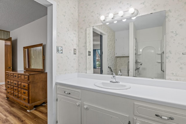 314 Cedar, Mount Pleasant, TX 75455 - full bath featuring wallpapered walls, wood finished floors, vanity, and a stall shower