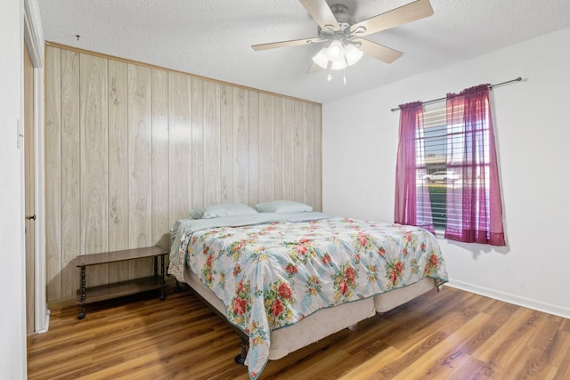 314 Cedar, Mount Pleasant, TX 75455 - bedroom with wood finished floors, wood walls, a textured ceiling, and a ceiling fan