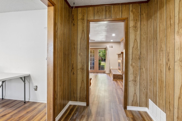 314 Cedar, Mount Pleasant, TX 75455 - hallway featuring wood finished floors, a textured ceiling, wooden walls, baseboards, and visible vents