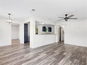 unfurnished living room with wood finished floors and ceiling fan with notable chandelier