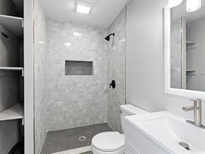 full bathroom featuring a tile shower, vanity, and toilet