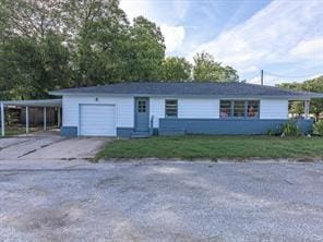 view of front of home featuring concrete driveway, an attached carport, a front yard, and a garage