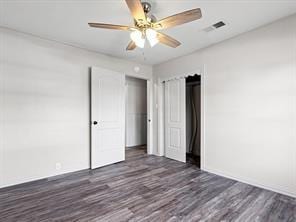 unfurnished bedroom with baseboards, a ceiling fan, visible vents, and dark wood finished floors