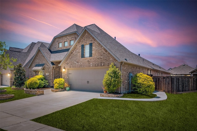 view of front facade featuring concrete driveway, a shingled roof, fence, a yard, and brick siding