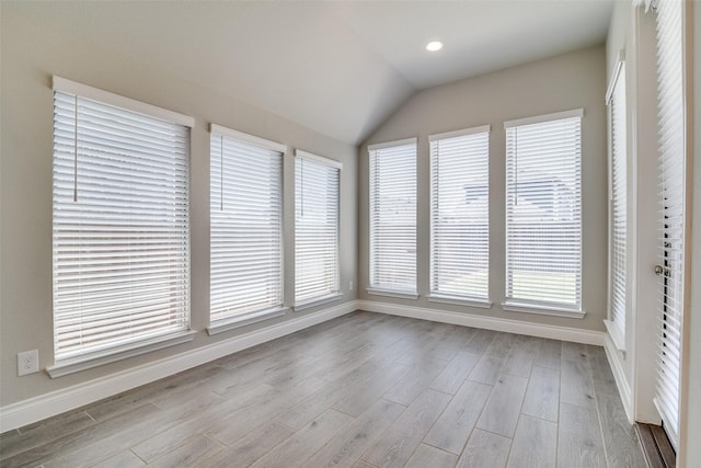 unfurnished sunroom featuring wood finished floors, baseboards, and vaulted ceiling