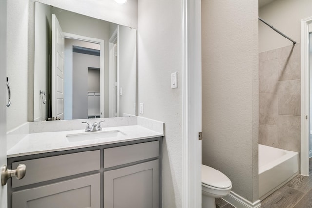 bathroom featuring wood finished floors, toilet, vanity, and  shower combination