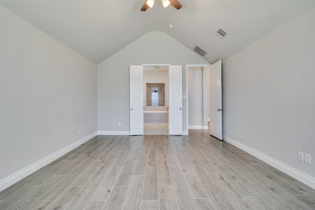 unfurnished bedroom featuring lofted ceiling, light wood finished floors, ensuite bathroom, and visible vents