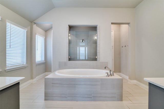 bathroom featuring lofted ceiling, a garden tub, vanity, and tile patterned flooring