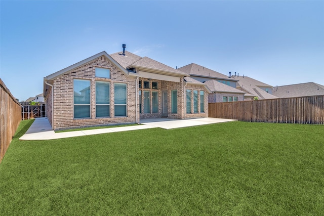 back of property with a fenced backyard, brick siding, a patio area, and a lawn