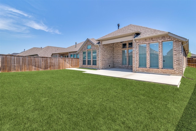 rear view of property with a fenced backyard, brick siding, and a yard