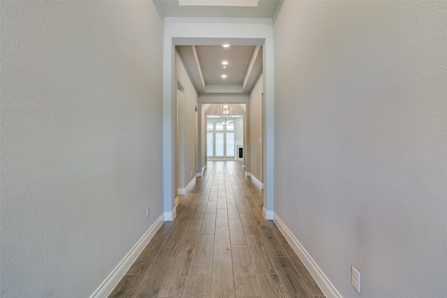 hall featuring baseboards, wood finished floors, and recessed lighting