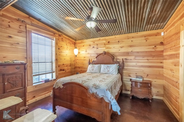 bedroom featuring ceiling fan, finished concrete floors, and wooden walls