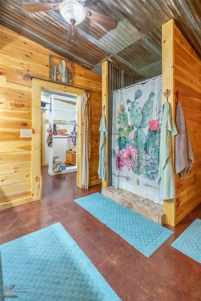 interior space with concrete flooring, wooden walls, and ceiling fan