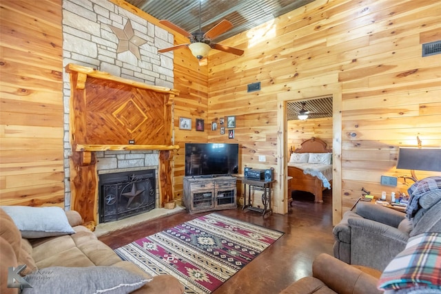living area featuring wooden walls, a stone fireplace, wood ceiling, and ceiling fan