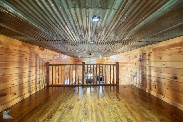 additional living space with wood walls and wood-type flooring