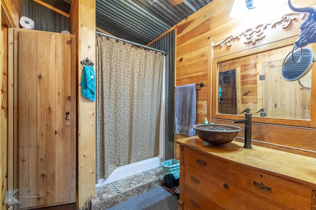 full bath featuring vanity, wooden walls, and a stall shower