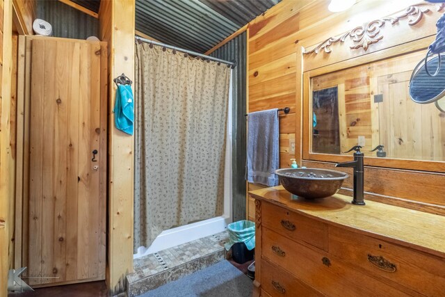 bathroom with wooden walls, vanity, and a shower stall
