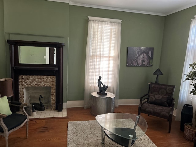 living room with baseboards, a tile fireplace, wood finished floors, and ornamental molding