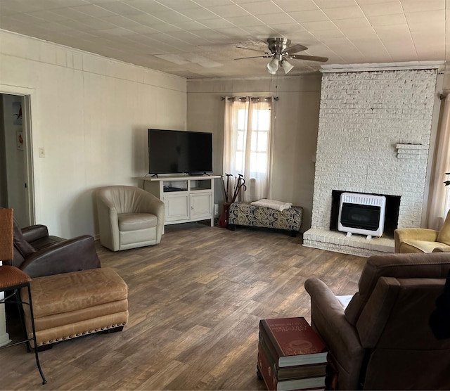living area with heating unit, ceiling fan, a fireplace, ornamental molding, and dark wood-type flooring