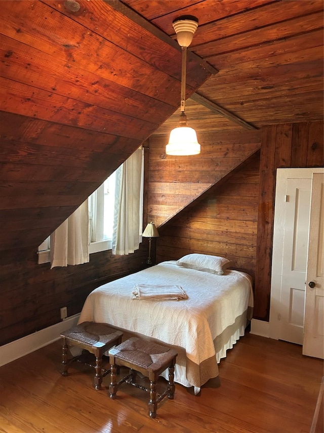 bedroom with wood ceiling, lofted ceiling with beams, wood finished floors, and wooden walls