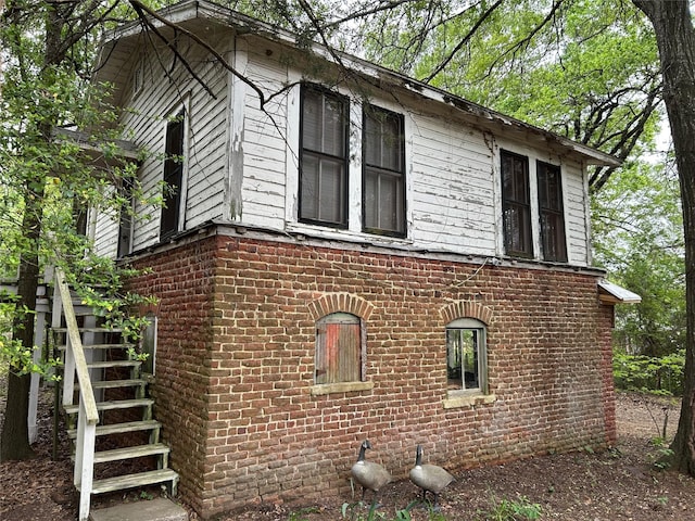 view of side of home with stairway and brick siding
