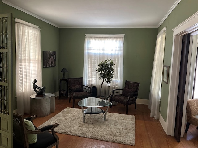 living area featuring baseboards, wood finished floors, and crown molding