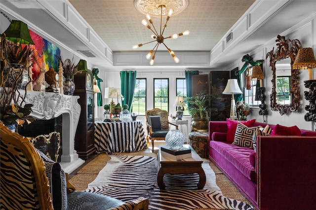 sitting room with a tray ceiling, visible vents, a notable chandelier, a fireplace with raised hearth, and crown molding