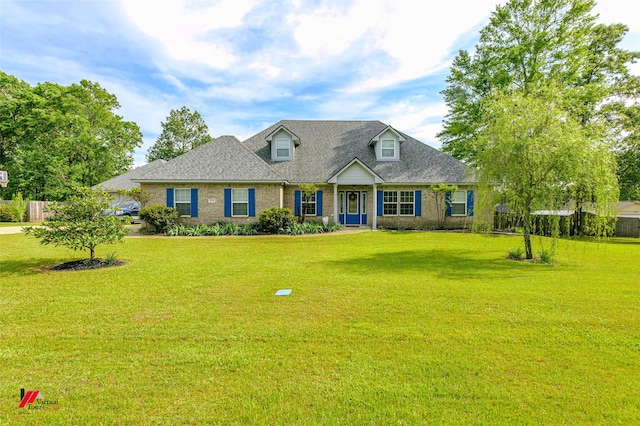 new england style home with brick siding, a shingled roof, a front lawn, and fence