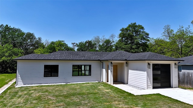 view of front of home with fence, an attached garage, driveway, roof with shingles, and a front yard
