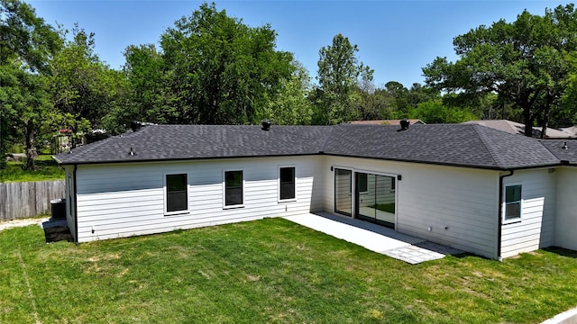 back of property with roof with shingles, fence, a yard, and a patio