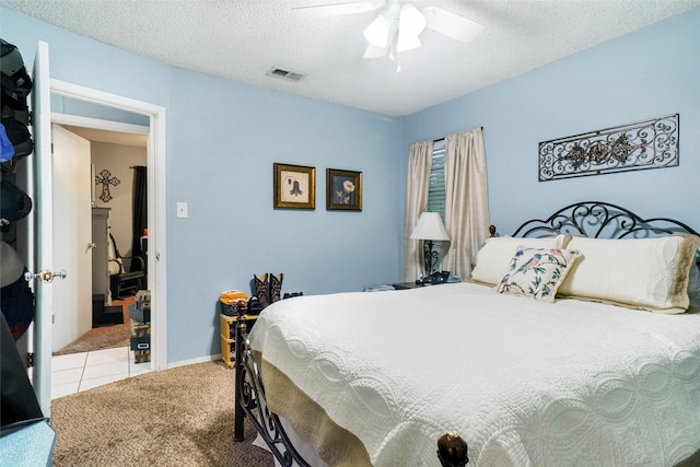 bedroom featuring visible vents, a textured ceiling, carpet, and ceiling fan