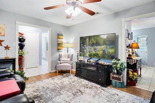 living room with baseboards, ceiling fan, wood finished floors, and visible vents