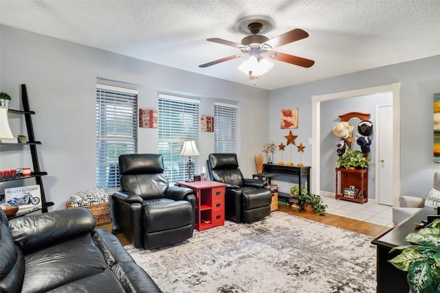 living room featuring a textured ceiling, ceiling fan, and wood finished floors