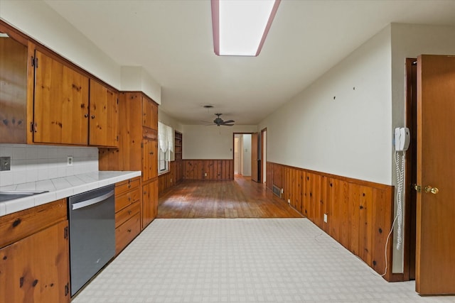 kitchen featuring stainless steel dishwasher, a wainscoted wall, and wooden walls