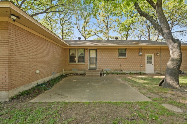 rear view of house with brick siding, a patio area, crawl space, and entry steps