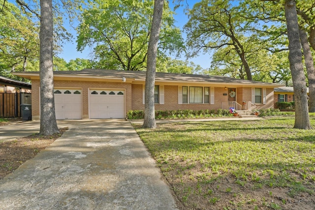 ranch-style home with driveway, brick siding, fence, a front lawn, and an attached garage