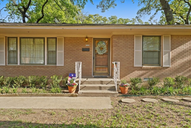 entrance to property featuring brick siding and crawl space