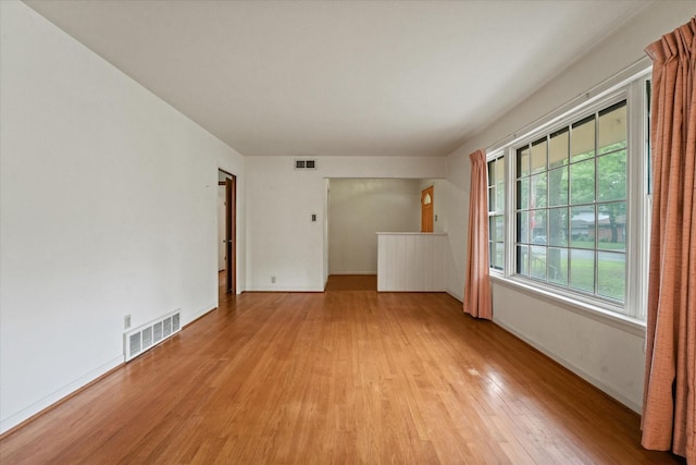 unfurnished room with visible vents, light wood-style floors, and baseboards