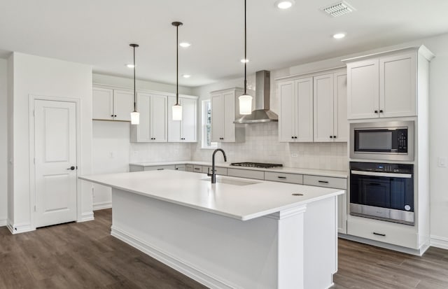 3470 Marginal Dr, Mckinney, TX 75071 - kitchen with stainless steel appliances, wall chimney exhaust hood, dark wood finished floors, backsplash, and a kitchen island with sink