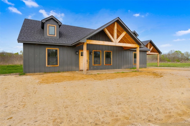 view of front facade featuring board and batten siding and roof with shingles