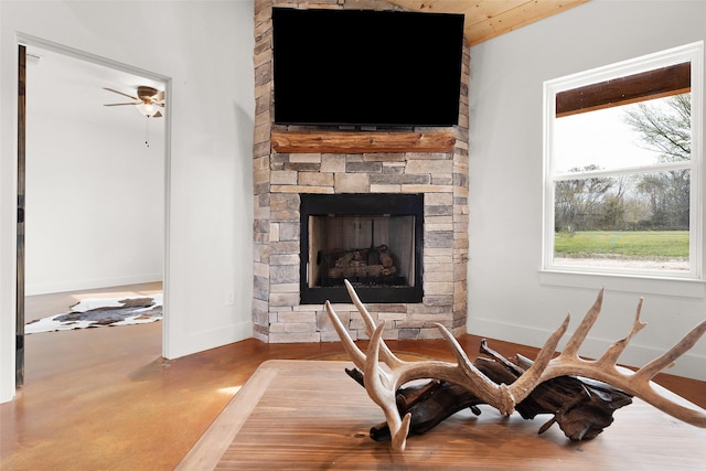 interior details featuring concrete floors, a stone fireplace, baseboards, and ceiling fan