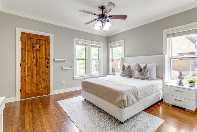 bedroom featuring wood finished floors, crown molding, and baseboards