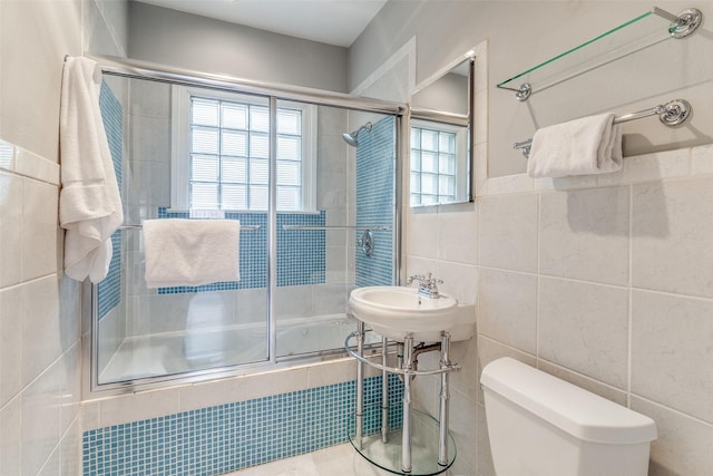 bathroom with tiled shower / bath, tile walls, and toilet