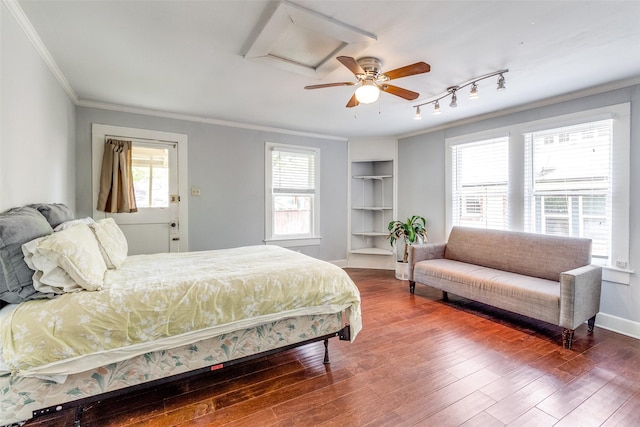 bedroom with rail lighting, baseboards, ornamental molding, and wood finished floors