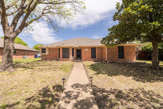 ranch-style house featuring fence, a shingled roof, a front lawn, and brick siding